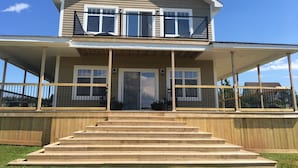 Une maison à deux étages dotée d’un porche et d’un escalier en bois menant à l’entrée.