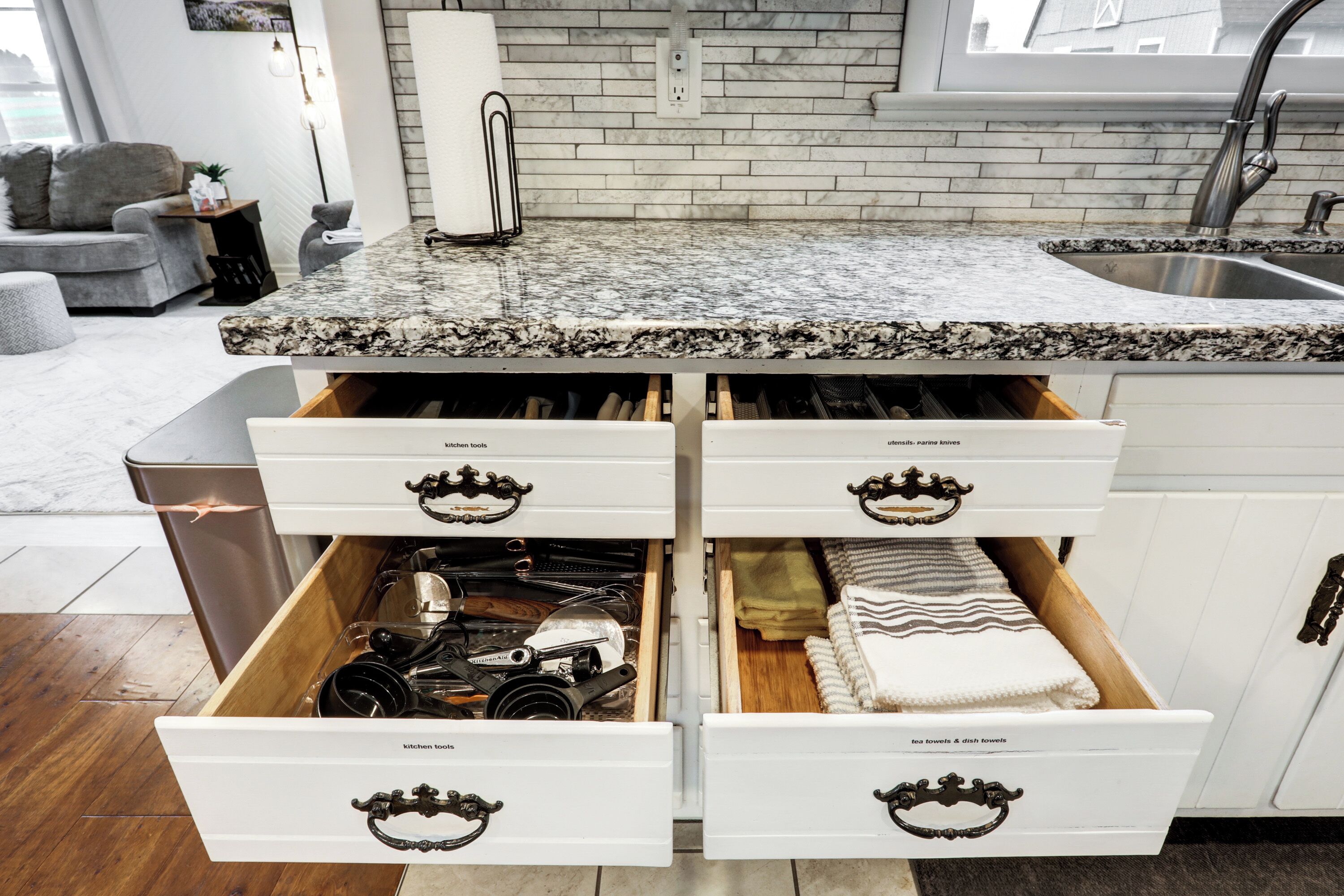A kitchen with white cabinets, a granite countertop, and a stainless steel sink.