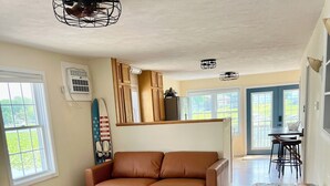 Un vaste espace de vie comprenant un canapé en cuir marron, une table basse en bois et un coin repas avec une table et des chaises.