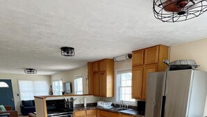 Une cuisine moderne avec des meubles en bois, des appareils électroménagers en acier inoxydable et un coin repas comprenant une table et des chaises.