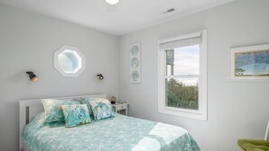Une chambre à coucher avec un lit, une fenêtre et des œuvres d’art murales.
