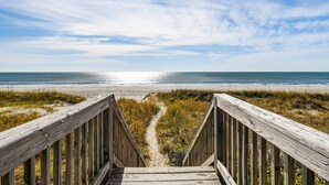 Une promenade en bois menant à une plage, avec un ciel dégagé.