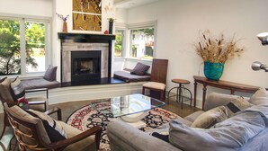 Un salon chaleureux avec une cheminée, un coin salon et une vue sur l’extérieur.