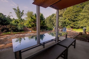 Relax under a shaded pergola surrounded by lush greenery and a serene pond.