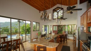 A spacious kitchen with a large island, wooden cabinets, and a view of the mountains. - Tropical Villa with Spectacular Views!   (Dominical)
