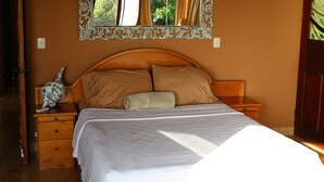 A bedroom with a wooden bed, two pillows, a bedside table, and a nightstand. - Tropical Villa with Spectacular Views!   (Dominical)