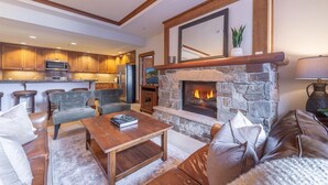 A cozy living room with a stone fireplace, leather sofas, and a wooden coffee table. - Cozy Village at Northstar Condo w/ Peek-A-Boo View of Skating Rink! (Truckee)