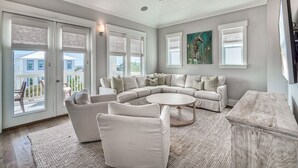 A spacious living room with a sectional sofa, a round coffee table, and a large window with blinds. - Lavish Coastal Getaway w/Media Room | 3 Min to Beach | Steps to Pool | 6 Bikes (Inlet Beach)