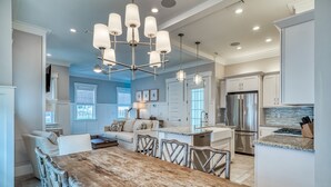 A spacious kitchen with a central island, stainless steel appliances, and a modern chandelier. - Lavish Coastal Getaway w/Media Room | 3 Min to Beach | Steps to Pool | 6 Bikes (Inlet Beach)