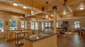 A spacious kitchen with wooden cabinets, a central island, pendant lighting, and a fireplace. - Home Theater, Hot tub & Huge Covered Patio! Stunning Home 2 Miles from Town! (Leavenworth)
