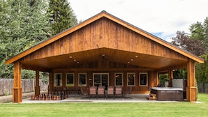 A wooden cabin with a covered patio, outdoor seating, and a hot tub. - Home Theater, Hot tub & Huge Covered Patio! Stunning Home 2 Miles from Town! (Leavenworth)