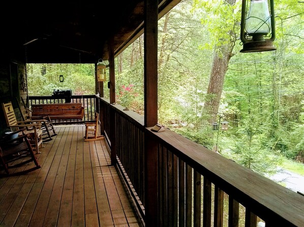 A wooden deck with benches and a lantern, overlooking a forested area. - Lazy Bear's Den (Sevierville)