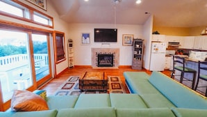 A living room with a sofa, a fireplace, a television, and a kitchen area.