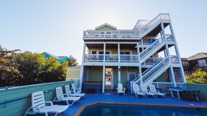 A multi-story building with a pool area, including lounge chairs and a staircase.