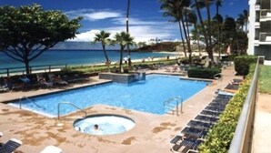 Un espace piscine doté d’un jacuzzi, de chaises longues et de palmiers.