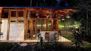Eine Holzhütte mit großen Fenstern, hängenden Pendelleuchten und einer Terrassenfläche.