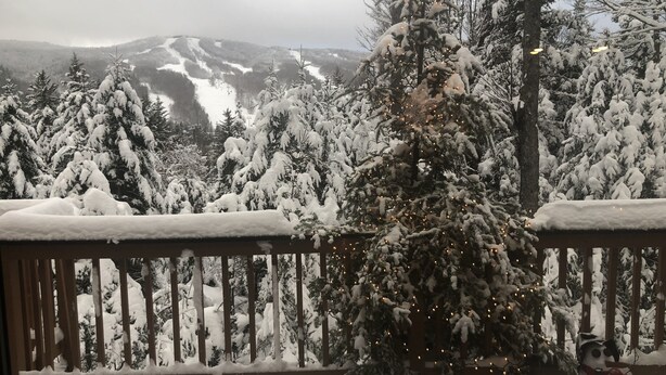 Una terraza cubierta de nieve con un árbol de Navidad y un muñeco de nieve.