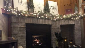 Una sala de estar acogedora con chimenea, un perro y decoración festiva.