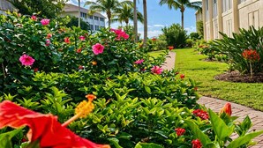 A well-maintained garden with various flowering plants and a pathway leading to a building.