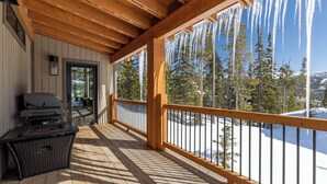 Un terrazzo in legno con vista su alberi e montagne innevate.