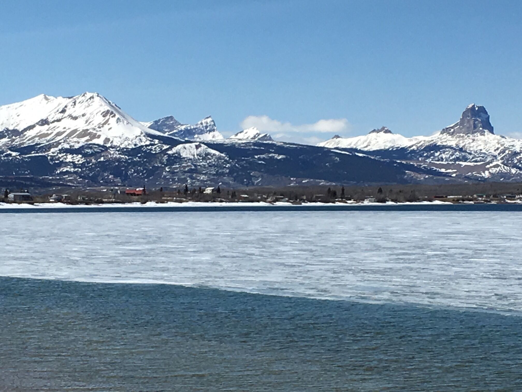 Ein weiter Blick auf eine Berglandschaft mit schneebedeckten Gipfeln und einem zugefrorenen See im Vordergrund.