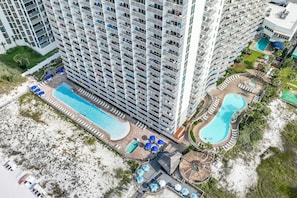 Un hôtel de grande hauteur doté de nombreux balcons, d’une grande piscine et d’un espace piscine séparé.