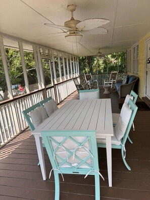 A covered outdoor patio with a table and chairs, a ceiling fan, and a view of the outdoors. - Classic Style Sullivan's Island house - Very Charming! 1 block to beach & walk to fabulous dining! (Sullivans Island)