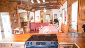 Una cocina con estufa, armarios de madera y un comedor con una mesa y sillas rosadas.