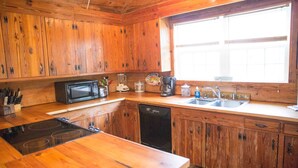 Una cocina de madera con microondas, estufa, fregadero y diversos electrodomésticos.