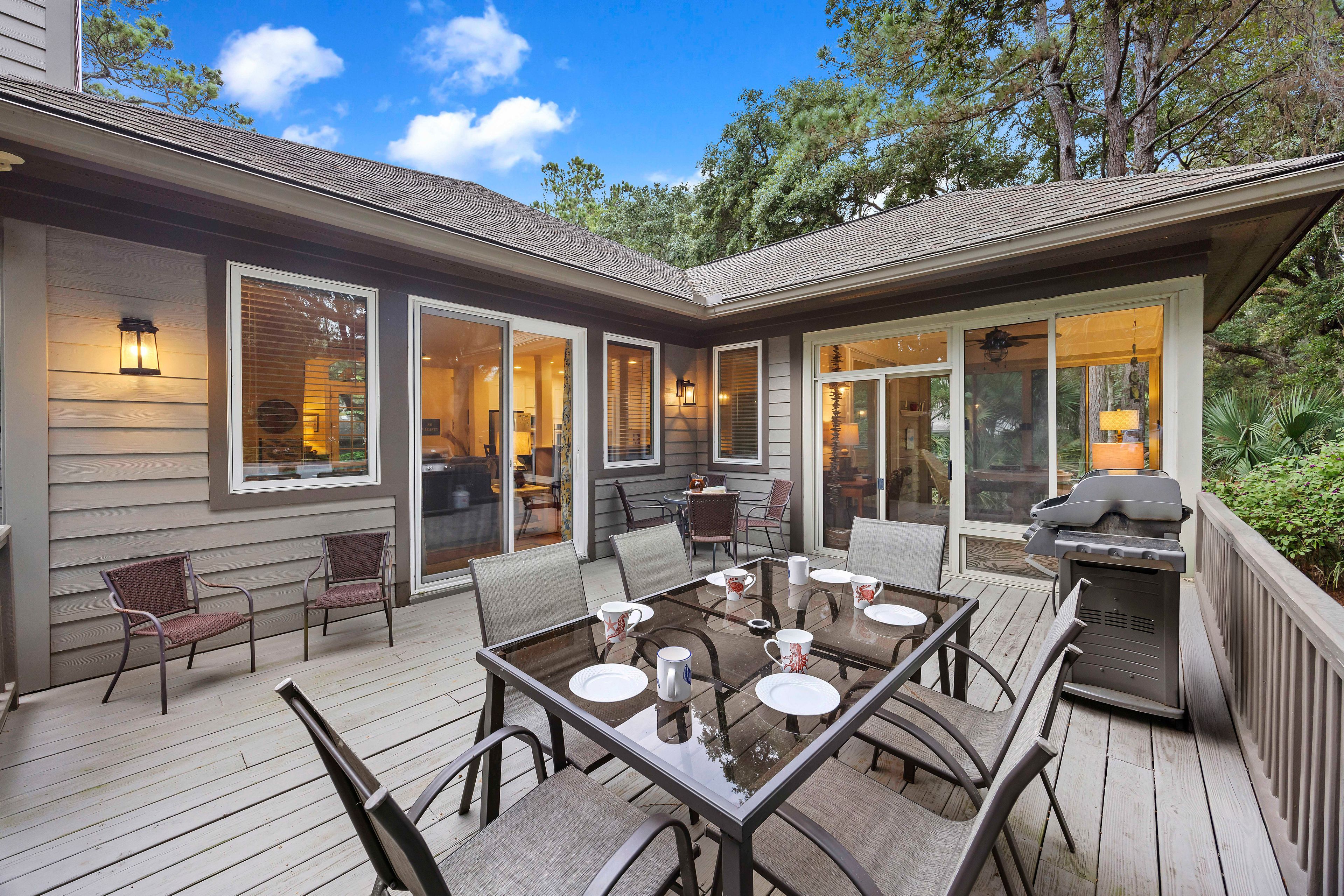 A covered patio with a dining table, chairs, and a grill.