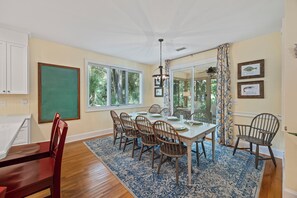 A dining area with a table set for four, surrounded by chairs, a chalkboard, and a window with blinds.