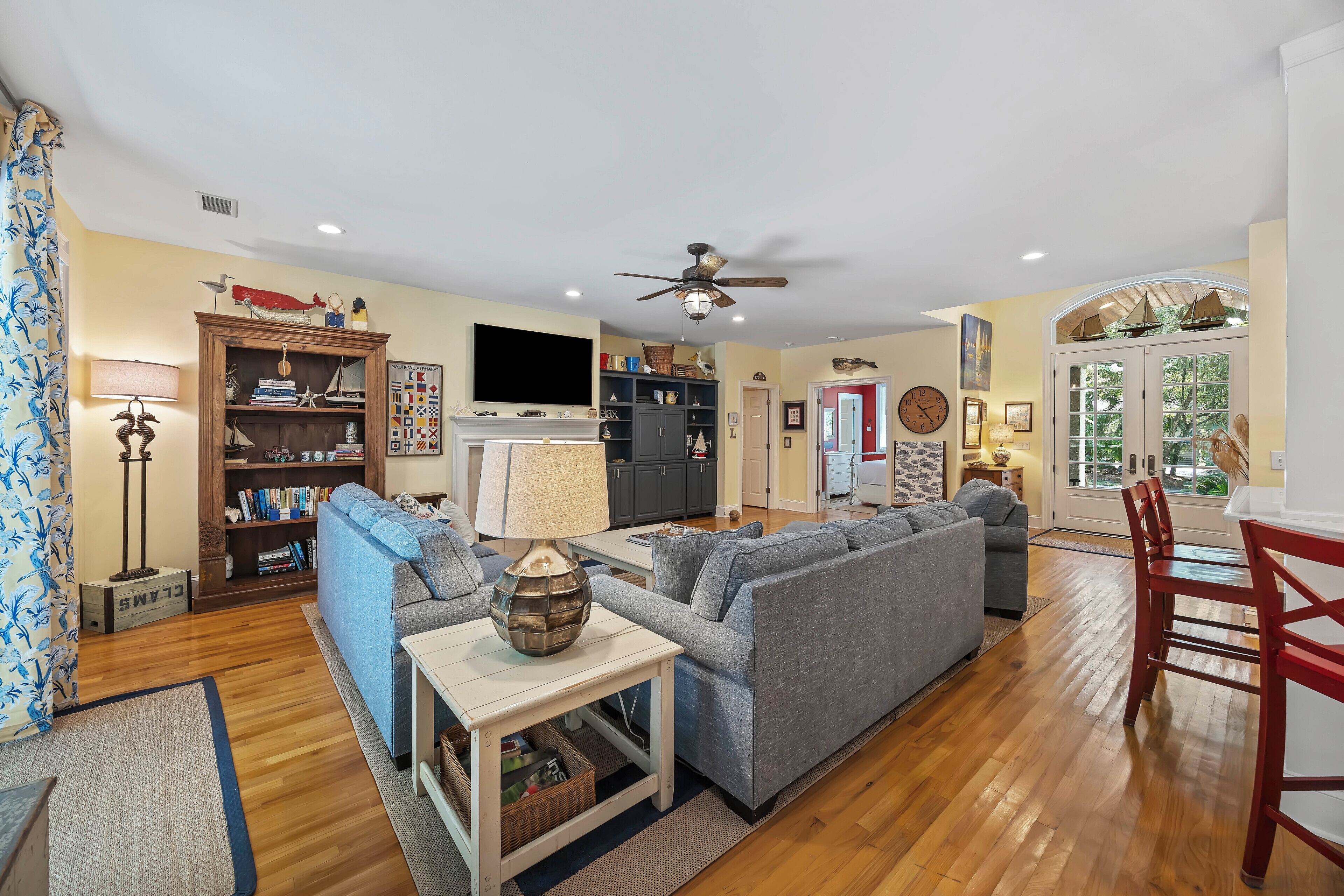A living room with a sofa, a table, a bookshelf, a TV, and a dining area with chairs.