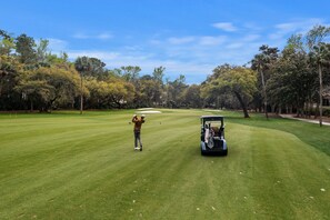 Un terrain de golf avec un golfeur et un chariot de golf.