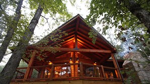 A wooden cabin with a balcony, surrounded by trees.