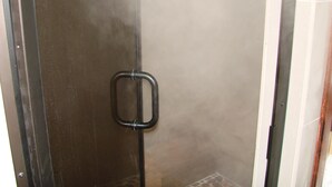 A shower with a glass door and a metal handle.