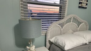 Une chambre à coucher avec un lit, une table de chevet avec une lampe et une fenêtre avec des stores.