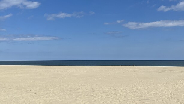 Une plage avec un ciel dégagé et une mer calme.