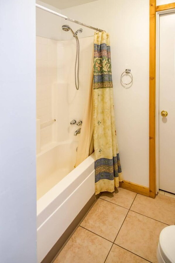 Un baño con bañera, ducha e inodoro.