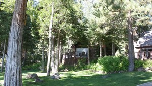 A cabin surrounded by tall trees and a well-maintained lawn. - Cozy Private Lakefront Cottage Surrounded By Lush Trees (Carnelian Bay)