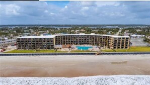 Ein mehrstöckiges Hotel mit Pool und Blick auf den Strand.