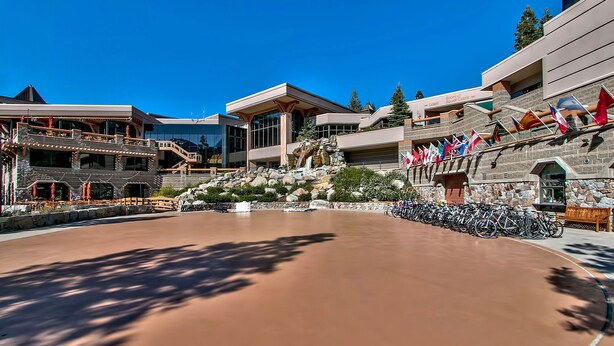Un hotel moderno con un amplio patio, arquitectura de piedra y una fila de banderas.