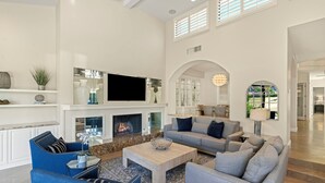 A spacious living room with a fireplace, a flat-screen TV, and comfortable seating.