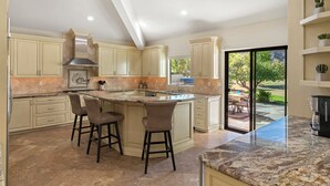 A spacious kitchen with a large island, built-in cabinets, and a view to the outdoors.