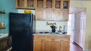 Une cuisine avec des meubles de rangement en bois, un réfrigérateur noir, un évier et une cuisinière.