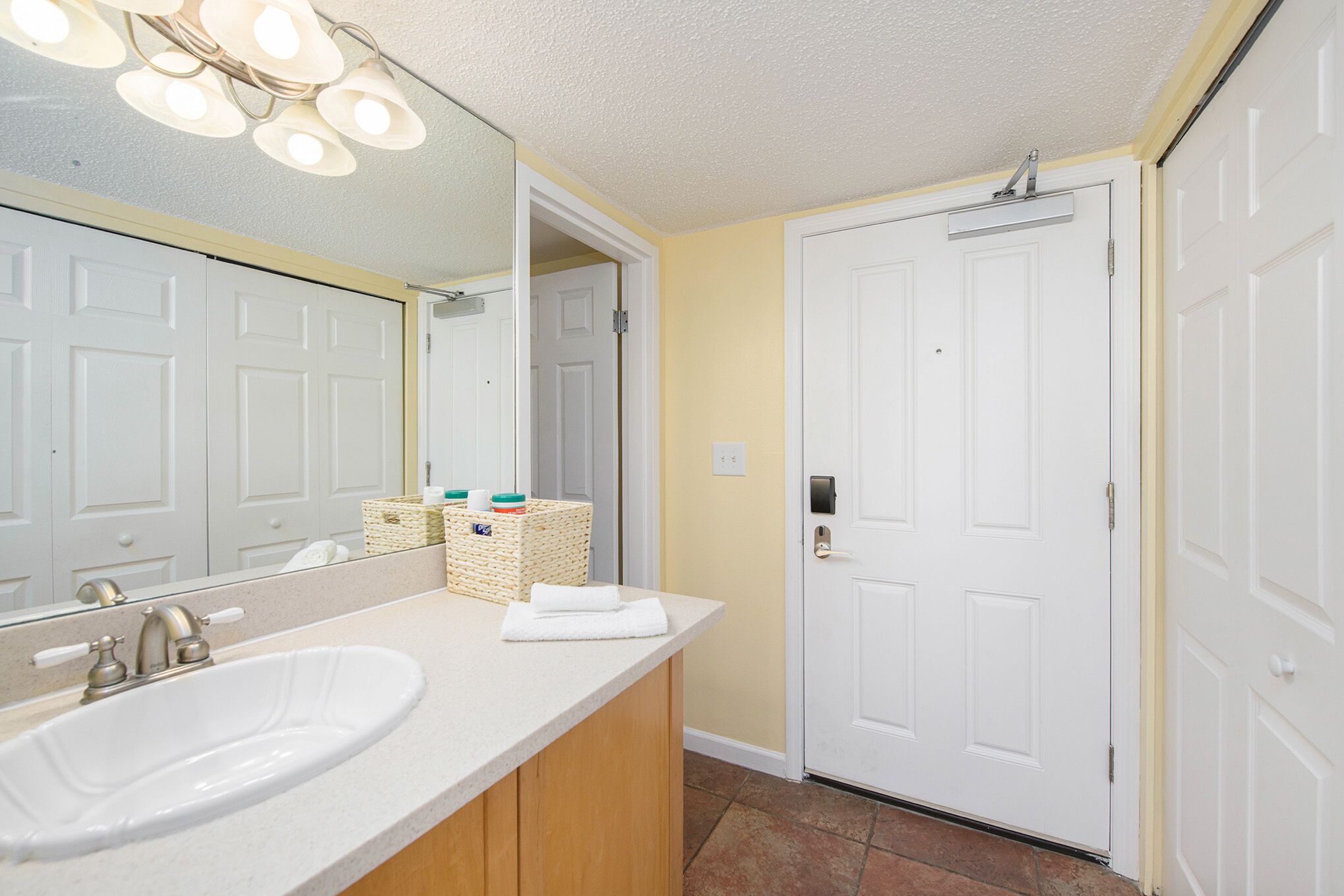 A bathroom with a white sink, mirror, and white door.