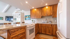 Una cocina con armarios de madera, horno empotrado y una isla grande con pileta.