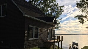 A house with a deck overlooking a body of water. - Waterfront Lake House - built in 2017 on shoreline & dog friendly (Swanton)