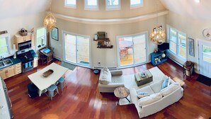 A spacious living area with a dining table, sofa, and a kitchen in the background. - Waterfront Lake House - built in 2017 on shoreline & dog friendly (Swanton)