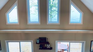 A room with a sloped ceiling, three skylights, and a wooden table with chairs outside. - Waterfront Lake House - built in 2017 on shoreline & dog friendly (Swanton)