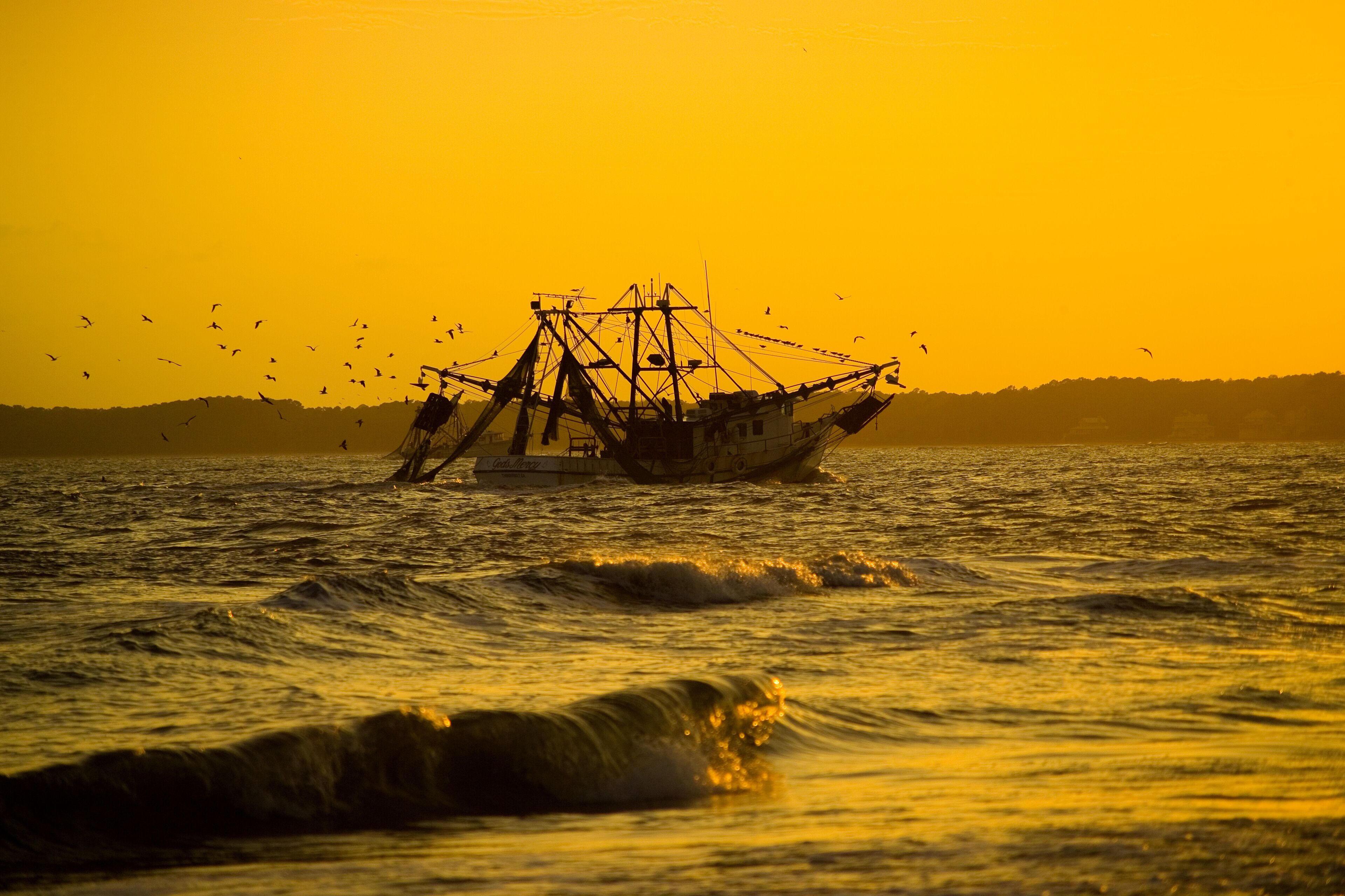 A fishing boat on the water during sunset.